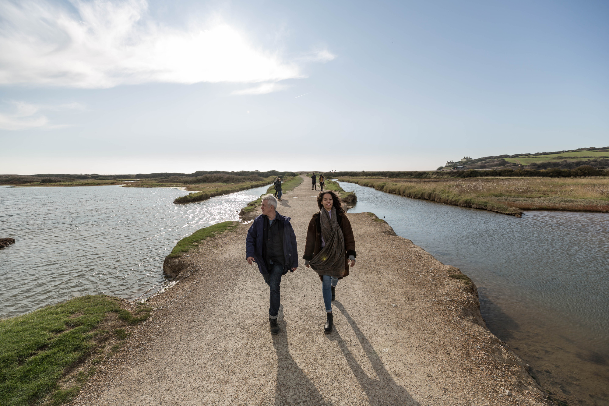 People walking along a stoney path near the coast