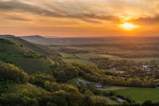 Rolling green hills and fields at sunset