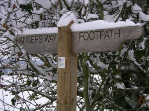 A finger post saying 'Hangers Way Footpath' covered in snow
