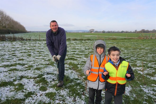 Russell Holmes, Assistant Forestry Manager at Goodwood Estate, with children from The March Primary School planting trees in a field on the Goodwood Estate