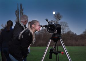 A telescope in an open field is being used to view the night sky