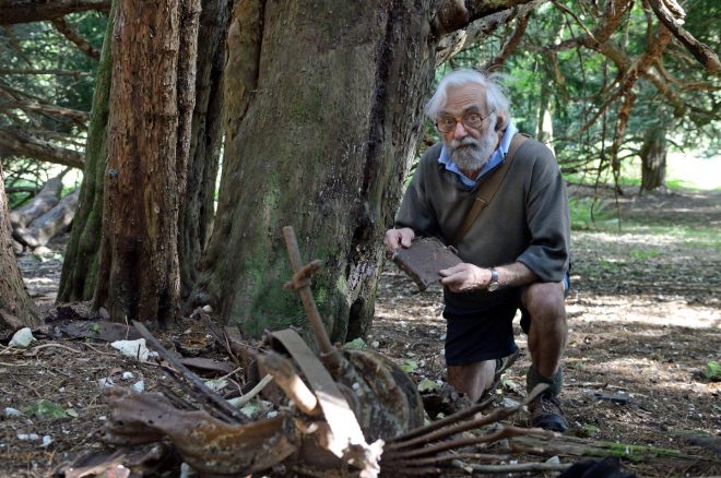 The late Richard Williamson crouching below a tree at Kingley Vale with some finds 