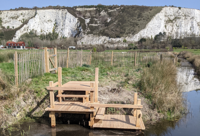 An image showing a newly installed wooden jetty by a river. In the background are white chalk cliffs